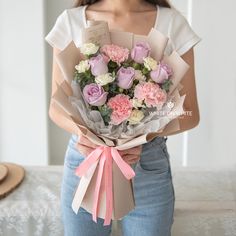 a woman holding a bouquet of pink and white flowers