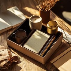 a wooden table topped with two books and cups on top of each other next to a plant