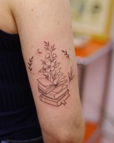 a woman with a tattoo on her arm has a book and flowers in the shape of a heart