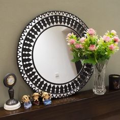 there is a vase with flowers in front of a mirror on a shelf next to a clock