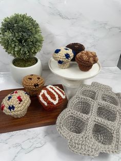 crocheted toys are sitting on a table next to a potted plant and plate