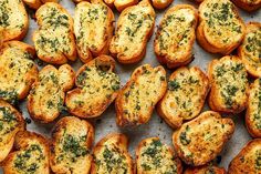 some toasted breads with cheese and herbs on them are sitting on a baking sheet