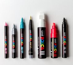 several markers and pens lined up on a white surface