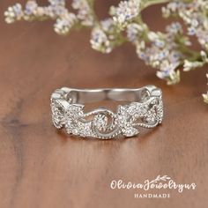 a wedding ring sitting on top of a wooden table next to some flowers and greenery