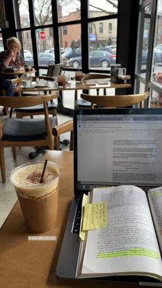 an open book sitting on top of a laptop computer next to a cup of coffee