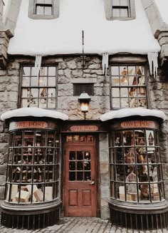 an old stone building with snow on the roof and window panes in front of it