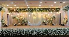 a stage decorated with white flowers and greenery for a wedding or event venue setting