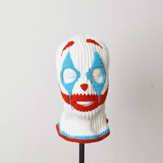 a knitted clown mask with red, white and blue paint on it's face