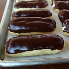 chocolate covered doughnuts sitting on top of a cookie sheet in a baking pan