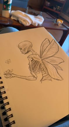 a drawing of a skeleton holding a butterfly on top of a table next to a coffee cup