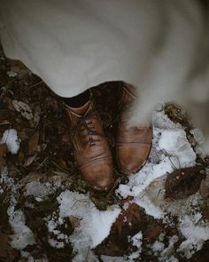 a pair of brown shoes standing on top of snow covered ground