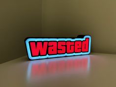 a red and blue sign that says wasted sitting on top of a white table in front of a brown wall