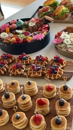 a table topped with lots of waffles covered in berries and other toppings