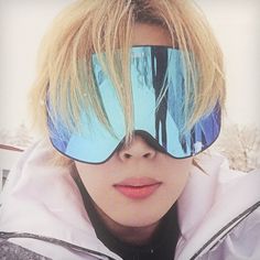 a woman wearing ski goggles with trees reflected in the lenses on her face and behind her is a snowboarder's head