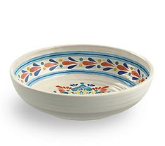 a white bowl with blue, orange and yellow designs on the rim is sitting in front of a white background