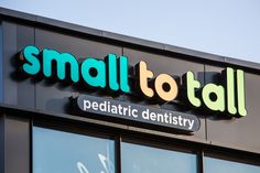 small to tall pediatric dentist sign on the side of a building with glass doors and windows