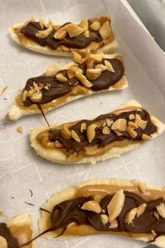 chocolate covered pretzels sitting on top of a piece of parchment paper with nuts