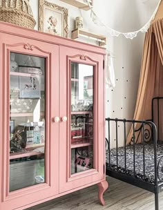 a pink china cabinet sitting next to a bed