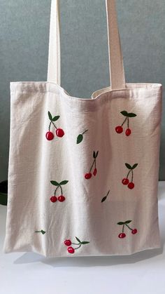 a white bag with cherries embroidered on it