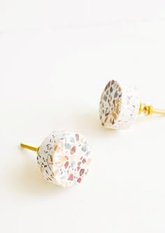 two pairs of white and gold earrings with small hearts on them, sitting next to each other