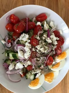 a salad with tomatoes, onions, cucumbers and hard boiled eggs