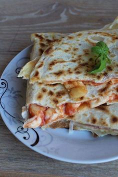 a white plate topped with three quesadillas on top of a wooden table