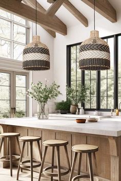 a kitchen island with stools in front of it and three hanging lights above it