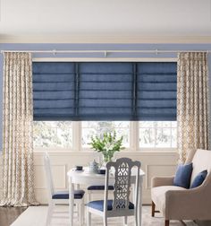 a dining room with blue walls and white furniture in the corner, along with two windows that have roman shades on them