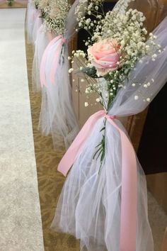 flowers are tied to the pews at a wedding ceremony with tulle and pink ribbon