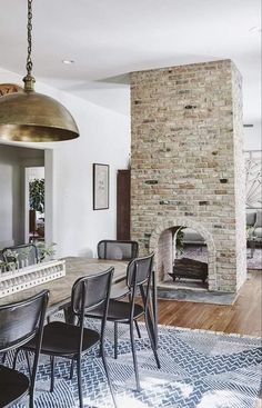 a dining room table with chairs and a fire place in the back wall behind it