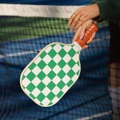 a person holding a tennis racquet with a green and white checkerboard design on it