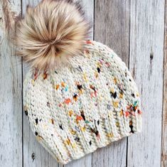 a white knitted hat with a brown pom - pom sitting on top of it