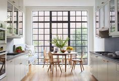 a table and chairs in a small kitchen with large windows that open up to the outside