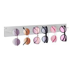 six pairs of sunglasses hanging on a white rack with pink and blue shades in them