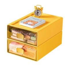 a yellow plastic box with two drawers and a clock on the top one drawer is filled with money