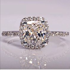 a cushion cut diamond ring with pave set diamonds on the band and halos around it