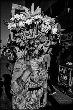 a black and white photo of a woman carrying flowers