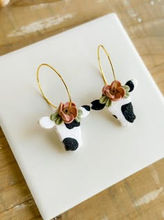 a pair of earrings with flowers on them sitting on a piece of paper next to some scissors