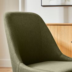 a green chair sitting on top of a hard wood floor next to a wooden wall