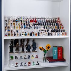 a shelf filled with lots of toy figurines on top of white shelving