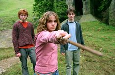 three young people are standing in the grass with a baseball bat and looking at the camera