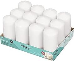 twelve white candles in a cardboard box