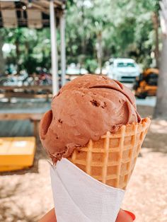 a hand holding an ice cream cone with chocolate frosting