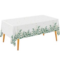 a white table cloth with green flowers and gold polka dots on the top, sitting on wooden legs