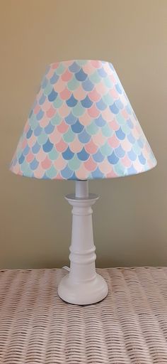 a lamp that is sitting on top of a table with a blue and pink shade