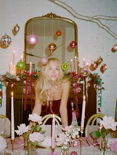 a woman sitting in front of a table with candles and ornaments on top of it