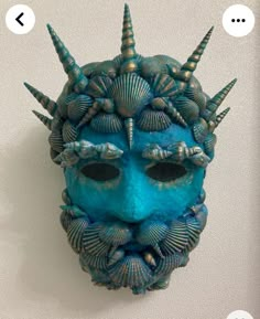 a blue mask with horns and seashells on it's face is shown