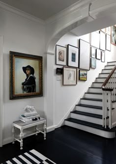 a staircase with pictures on the wall and a painting hanging above it in a home