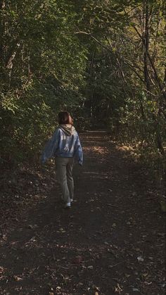 a woman walking down a path in the woods