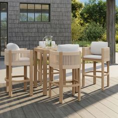 a wooden table and chairs sitting on top of a deck next to a building with windows